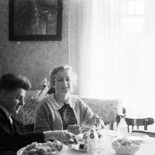Two people seated at a table, appearing to eat.