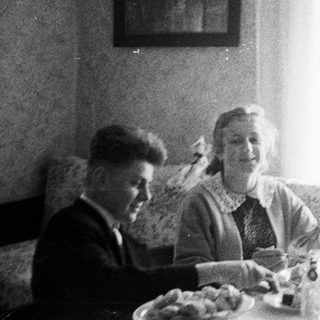 Two people seated at a table, appearing to eat.