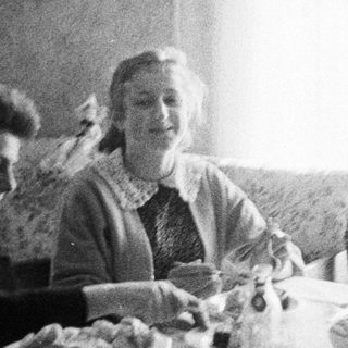 Two people seated at a table, appearing to eat.