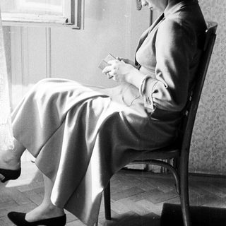 Woman seated, reading while looking down in a room.