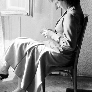 Woman seated, reading while looking down in a room.