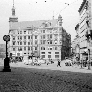 Black and white photo shows a bustling, historic city street scene.