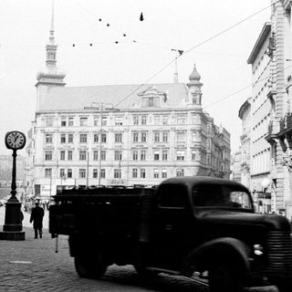 Vintage truck on street with buildings and people.