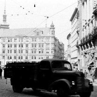 Vintage truck on street with buildings and people.