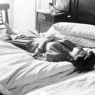 Woman lies in bed, relaxed, in a vintage bedroom.
