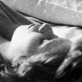Woman lies in bed, relaxed, in a vintage bedroom.