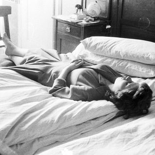 Woman lies in bed, relaxed, in a vintage bedroom.