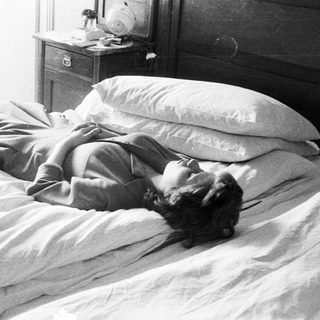 Woman lies in bed, relaxed, in a vintage bedroom.