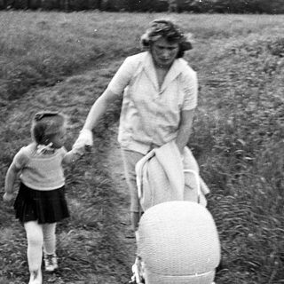 Woman walks along a path, holding a child's hand.