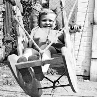 Black and white photo of a child on a swing.