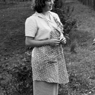 Couple standing outdoors, likely in a garden or farm setting.