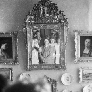 Portraits and decorative plates adorn a wall, partially obscured.