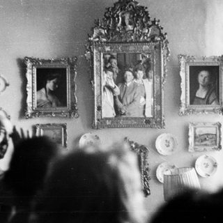 Portraits and decorative plates adorn a wall, partially obscured.