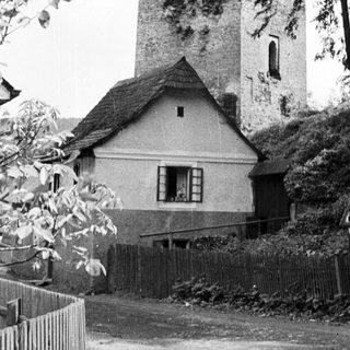 House next to a ruined stone tower and hillside.