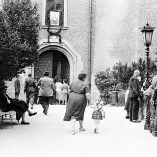 Here's a brief summary of the image: People and soldiers on a pathway near a building.