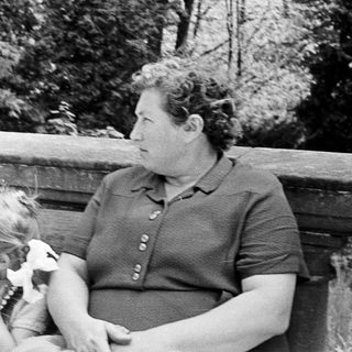 Here's a brief summary of the image: Woman and child sit on a bench outdoors.