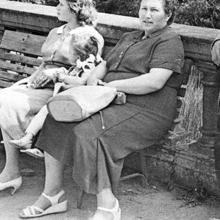 Black and white photo of three people on a bench.