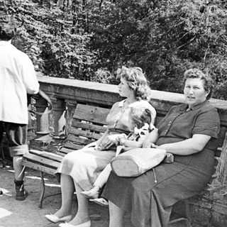 Black and white photo of three people on a bench.