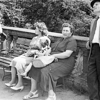 Black and white photo of three people on a bench.