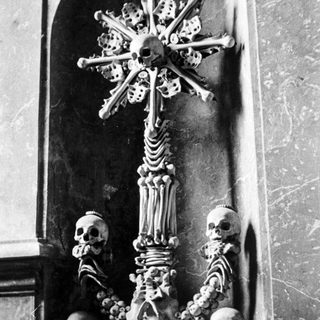 Bone sculpture depicting a cross with skulls and skeletal remains.
