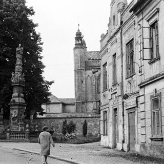 Monochrome street scene with statue, building, and a person.