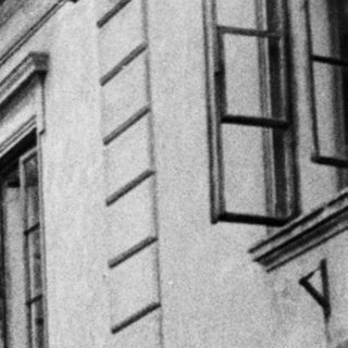 Monochrome street scene with statue, building, and a person.