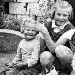 Three children pose outdoors in a black and white photograph.