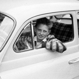 Young man smiles while leaning out of a car.