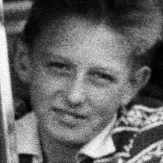 Young man smiles while leaning out of a car.