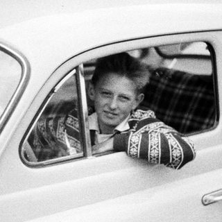 Young man smiles while leaning out of a car.