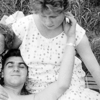 Three people relax in grass, posing for a portrait.