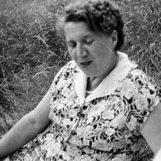 Black and white photo of a woman sitting in grass.