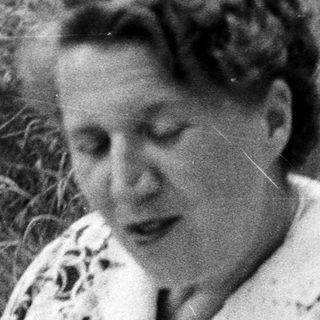 Black and white photo of a woman sitting in grass.