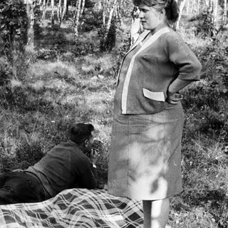 Couple relaxing outdoors on a blanket in a wooded area.