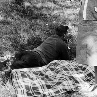 Couple relaxing outdoors on a blanket in a wooded area.