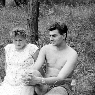 Three people sitting on a blanket outdoors in a field.