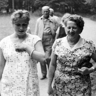 Black and white photo of women walking outdoors with baskets.