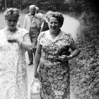 Black and white photo of women walking outdoors with baskets.