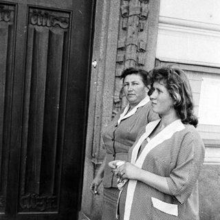 Two women stand outside a building in a black and white photo.
