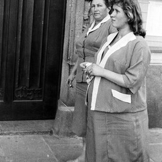 Two women stand outside a building in a black and white photo.