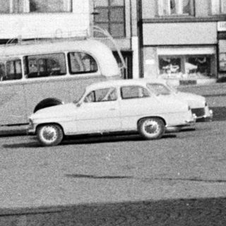Black and white photo of a town square with vehicles.