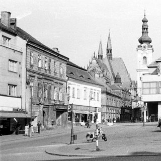 Black and white photo of a town square with vehicles.