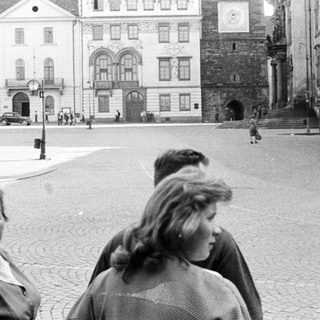 People walk through a cobblestone square with historic buildings.