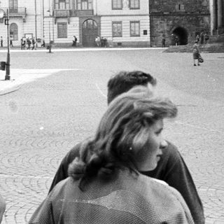 People walk through a cobblestone square with historic buildings.