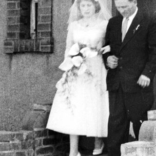 Bride and groom exit building, bird in ornate cage.