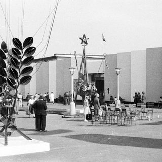Soviet pavilion with sculpture and crowd during an event.