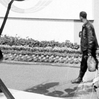 Sculpture of wheat on display, people observing the artwork.