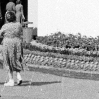 Sculpture of wheat on display, people observing the artwork.