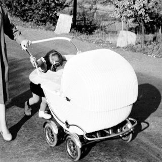 Woman pushes a baby in an ornate vintage pram.