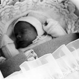 Black and white image of a baby sleeping in a crib.